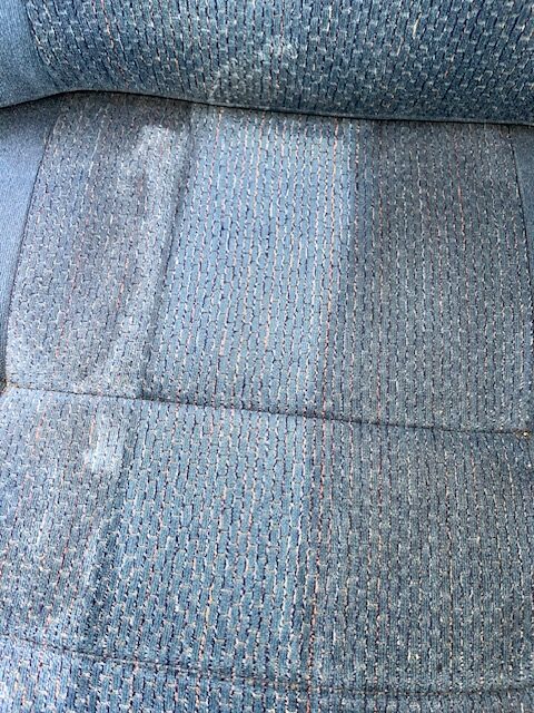 Close-up of a fabric seat showing a clean section contrasted with a stained