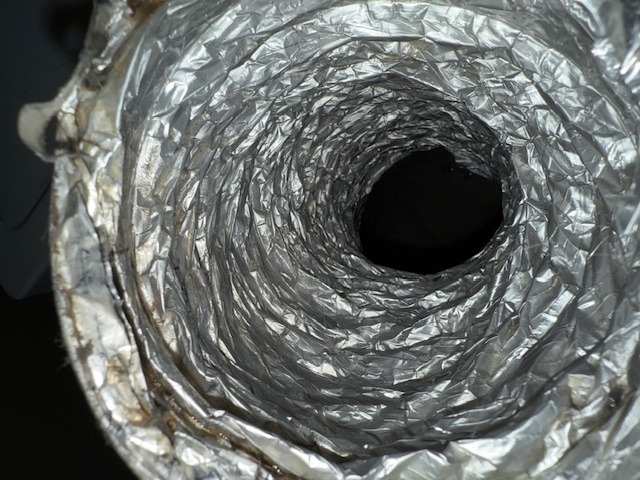 Metallic ducting viewed from the inside, showing its textured surface and circular shape