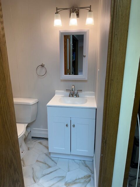 Small bathroom featuring a white vanity with a sink, a mirror above, and a modern light fixture