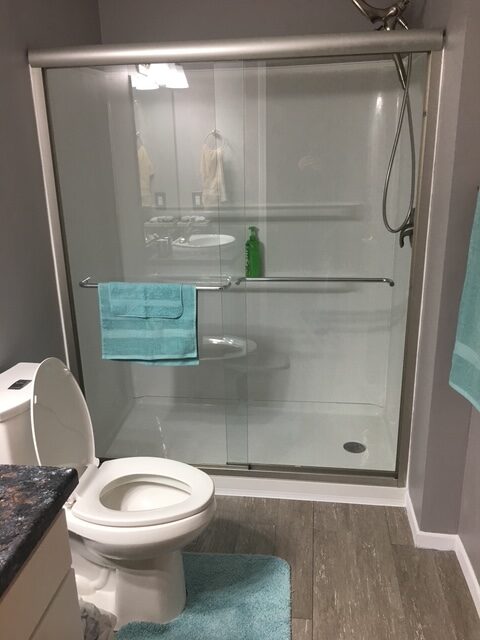 Modern bathroom featuring a glass shower, turquoise towels, and a toilet. The clean design highlights the contemporary style and functionality of the space.